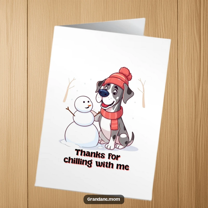 Funny Free Printable Thank You Card of a Great Dane in a winter hat building a snowman, expressing gratitude with playful charm.